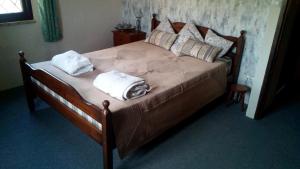 a wooden bed with two pillows and towels on it at Las Marrojas, secluded Tudor country cottage in Algarinejo