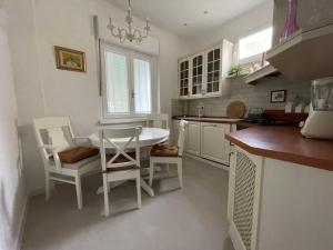 a white kitchen with a table and chairs in it at Linden Korzo with balcony in Rijeka