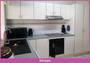 a kitchen with white cabinets and a black microwave at Estuary Parade House in Ross River