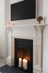 einen Kamin mit zwei Kerzen und einen Flachbild-TV darüber in der Unterkunft The Chesterfield Suite in London
