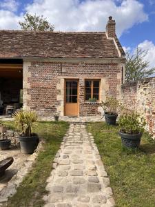 une maison en briques avec un chemin en pierre menant à une porte dans l'établissement Studio du Mont des Ormes, à Monchy-Humières