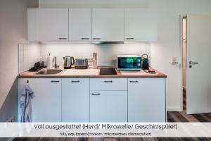 a kitchen with white cabinets and a microwave at "Neptun-Apartment" - Nähe Altstadt - Terrasse - Smart TV - Nespresso in Dresden