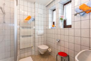 La salle de bains est pourvue de carrelage blanc, de toilettes et d'un lavabo. dans l'établissement Frühstücks- Pension Sonnblickhof, à Rauris