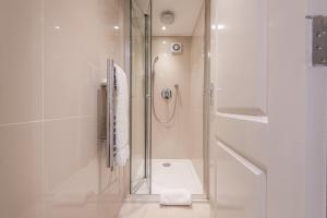 a bathroom with a shower with a glass door at Queensgate Court in London +76 photos