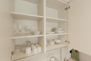 a kitchen with white shelves with glasses and plates at Penywern Apartment Earls Court in London