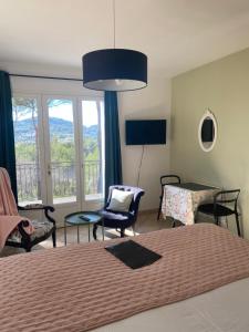 a bedroom with a bed and chairs and a large window at Une Pause en Provence in Le Beausset