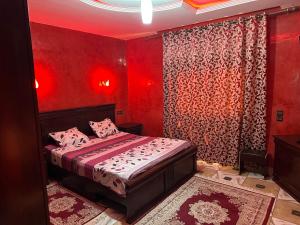 1 dormitorio con paredes rojas y 1 cama con almohadas rosas en appartement meublé à Laâyoune, en Laayoune