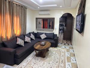 a living room with a black couch and a table at appartement meublé à Laâyoune in Laayoune