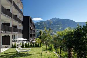 un hotel con un jardín con una montaña en el fondo en Landsitz Stroblhof, en Tirolo