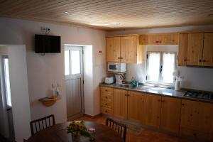 una pequeña cocina con armarios de madera y una mesa. en Casa da Eira, en Bordeiro