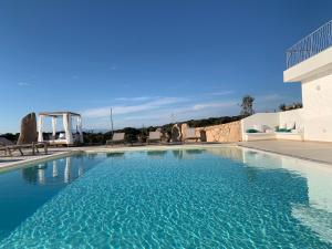 una piscina con acqua blu di fronte a un edificio di La Littighedda a Rena Majore