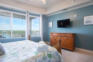 a bedroom with a bed and a dresser and a television at Levins Bend at The Wharf in Orange Beach