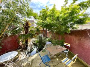 a patio with a table and chairs and trees at Maison de charme proche Futuroscope in Bonneuil-Matours