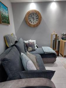 a living room with a couch and a clock on the wall at Bee Happy Apartament Wrzesnia in Września
