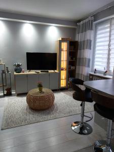 Una sala de estar con un televisor y una mesa y sillas. en Bee Happy Apartament Wrzesnia, en Września