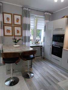 a kitchen with a table and two bar stools at Bee Happy Apartament Wrzesnia in Września