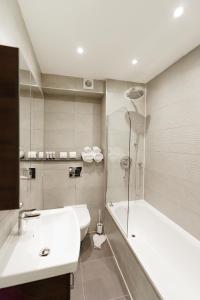 a bathroom with a sink and a tub and a toilet at Penywern Apartment Earls Court in London