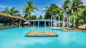 une piscine bordée de palmiers et un bâtiment dans l'établissement Le Grand Hôtel Diego, à Diego Suarez