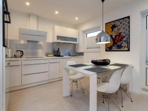 a white kitchen with a table and white chairs at Traumkoje im Herzen Westerlands strandnah Meer in Westerland (Sylt) +10 photos