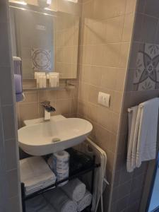 La salle de bains est pourvue d'un lavabo, d'un miroir et de serviettes. dans l'établissement Dimora Sasi Locazione Turistica, à Polignano a Mare