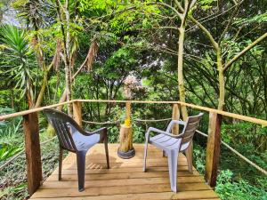 2 sillas sentadas en una terraza de madera con árboles en Beautiful house surrounded by nature with deck, en Medellín