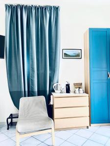 Zimmer mit einem Stuhl, einer Kommode und einem Vorhang in der Unterkunft Relax nel Centro Storico in San Nicola Arcella