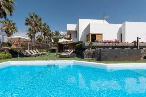 a swimming pool in front of a house at Villa Las Americas in Playa de las Americas