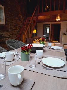 a table with white plates and red flowers on it at Le Chalet - Maison de vacances in La Roche-en-Ardenne