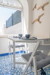 una sala da pranzo con tavolo e sedie bianchi di La Casetta a Capri