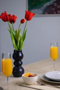 a table with two glasses of orange juice and red flowers at Deluxe Apartment and Studio "Nona Fa" in Rijeka