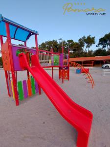 un parque infantil con un tobogán rojo en la playa en PAMARA Mobile Home en Biograd na Moru