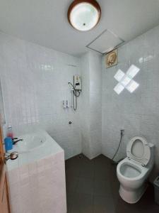 a white bathroom with a toilet and a sink at Marin House Pattaya in Pattaya North