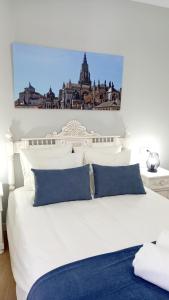 a white bed with blue pillows in a bedroom at Narciso Tomé en San justo 4 in Toledo