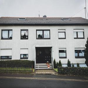 a white house with a dog sitting in the doorway at Gemütliche Ferienwohnung für 4 Personen in Baumholder