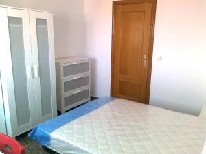 um pequeno quarto com uma cama e uma porta de madeira em PISO CON VISTAS em Burjasot