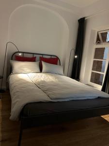 a bed with red and white pillows and a window at Apartment im Geteviertel - citynah in Bremen