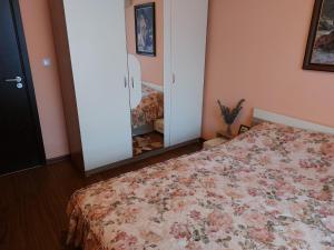 a bedroom with a bed with a floral bedspread and a mirror at Вилла Астория 3 in Elenite