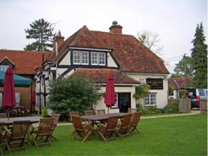 a table and chairs with umbrellas in front of a house at The New Inn in Reading