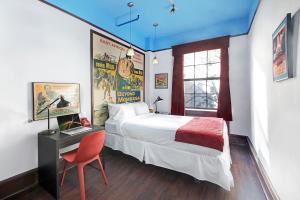 1 dormitorio con 1 cama y escritorio con silla roja en Chelsea Pines Inn, en Nueva York
