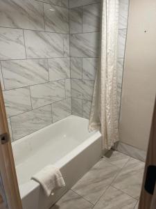 y baño con bañera blanca y azulejos de mármol. en Bear Mount Inn & Suites en Pigeon Forge