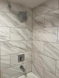 y baño con ducha y azulejos de mármol blanco. en Bear Mount Inn & Suites en Pigeon Forge