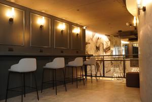 a bar with white stools in a room at The Londoner Hotel Sliema in Sliema