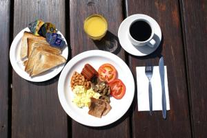 een tafel met twee borden ontbijtproducten en een kopje koffie bij Nyani Lodge Dinokeng in Pretoria