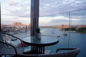 a table in a balcony with a view of a river at The Londoner Hotel Sliema in Sliema