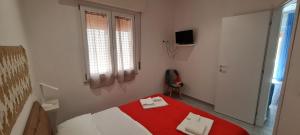 La Siciliana Trapani Apartment في تراباني: غرفة نوم بسرير احمر وبيض ونافذة