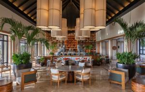ein Restaurant mit Tischen, Stühlen und Pflanzen in der Unterkunft Fairmont Mayakoba Riviera Maya - All Inclusive in Playa del Carmen