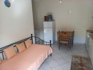 a bedroom with a bed and a table and a refrigerator at Stefkas apartment1 in Patra