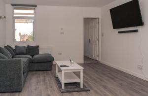a living room with a couch and a table at Spacious 4 Bedroom Apartment in Coventry