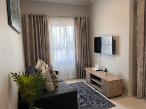 uma sala de estar com um sofá preto e uma televisão em 93 on new unique and classy em Midrand