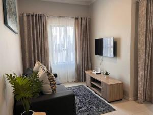 a living room with a black couch and a flat screen tv at 93 on new unique and classy in Midrand